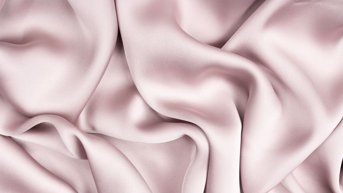 Close-up of light pink satin in soft folds.