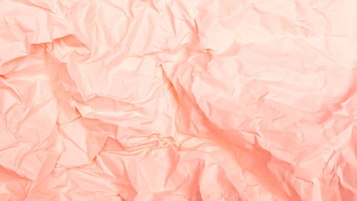 Crumpled pale pink paper, lit softly.