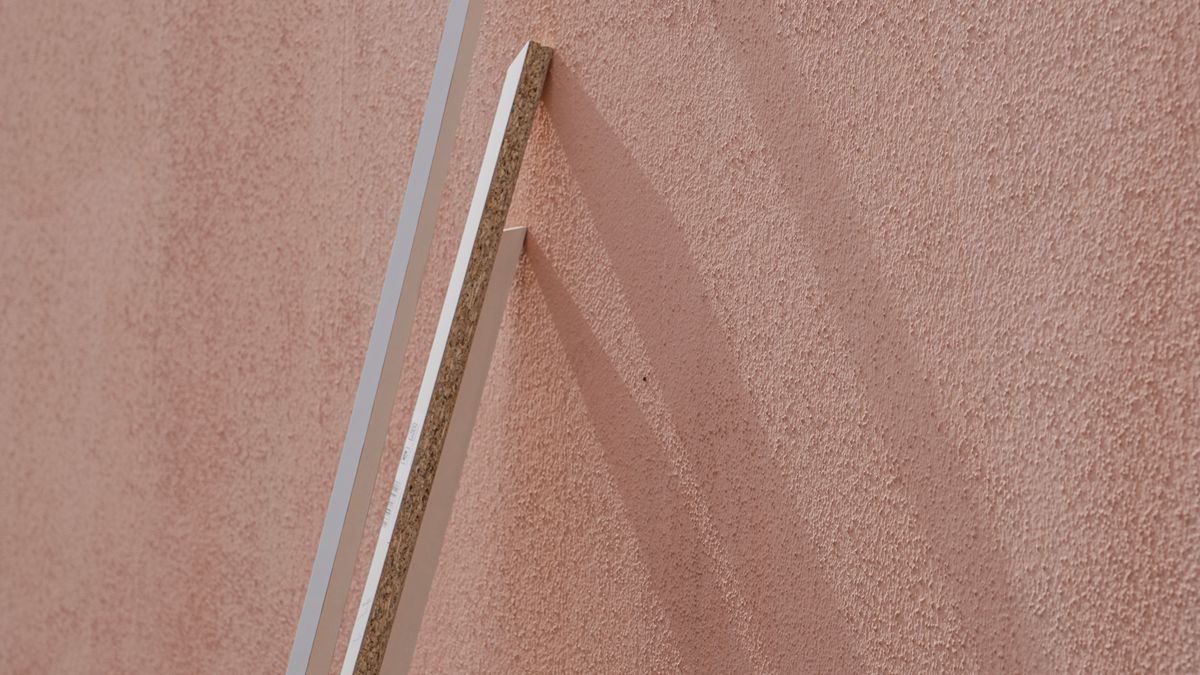 Morning sunlight and a long shadow falling across a pink wall.