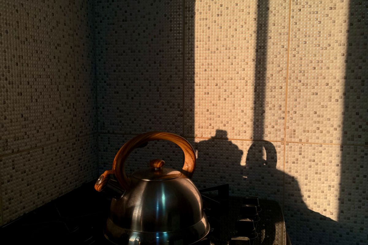 A stovetop kettle in a kitchen, lit by morning light through a blind.
