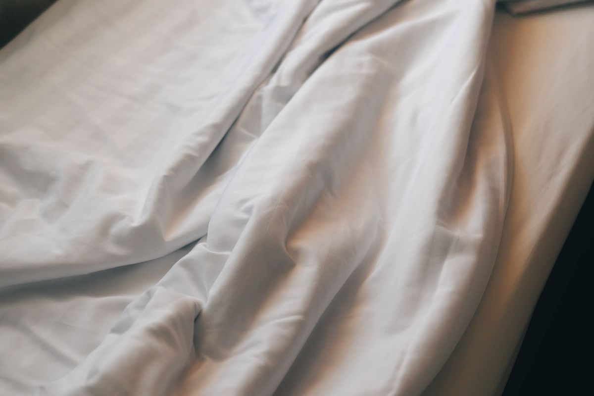 Crumpled white bedding in soft morning light.