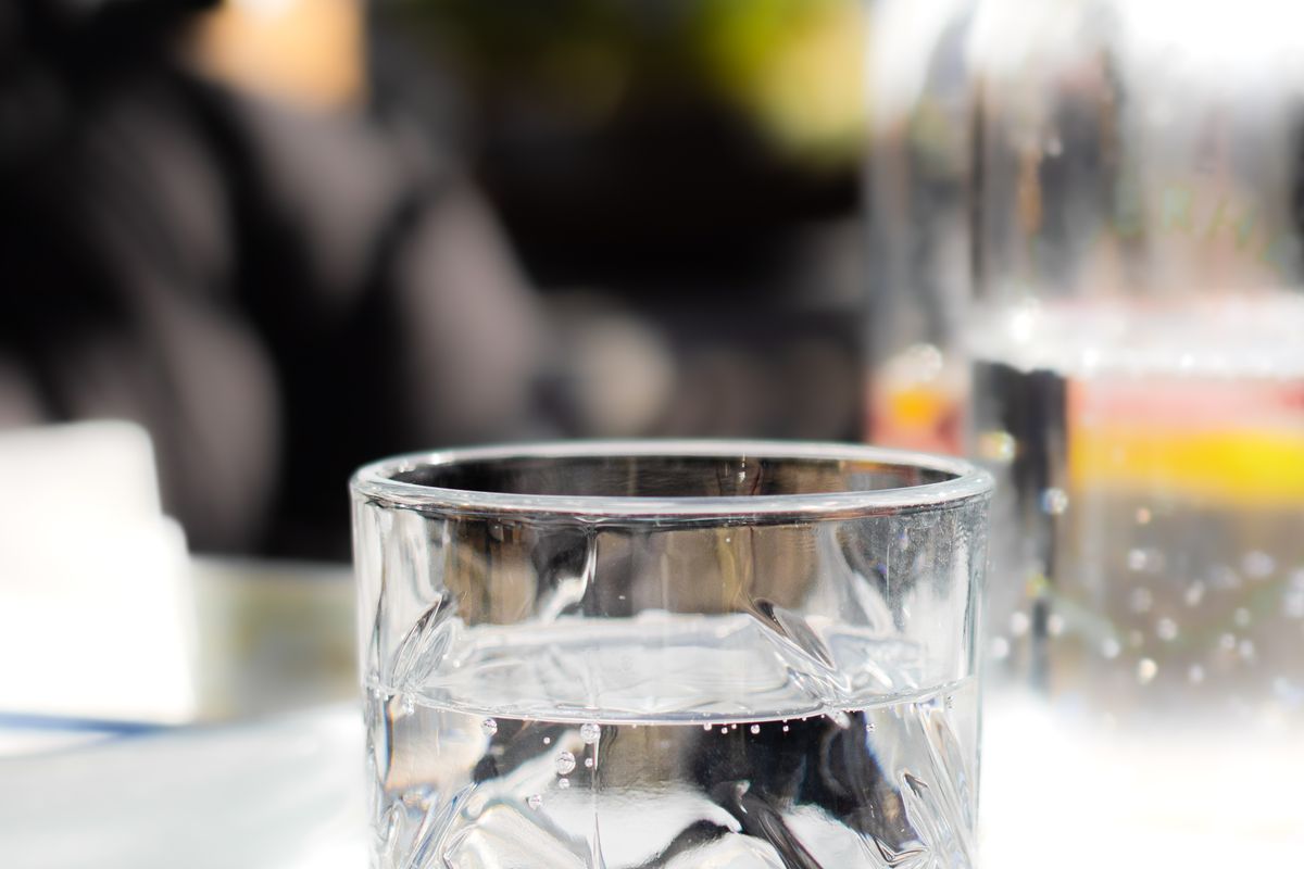 A glass of water on a table in bright morning light.
